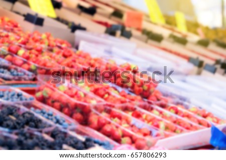 Strawberry and blueberry on green grocery market, out of focus, blurred image.