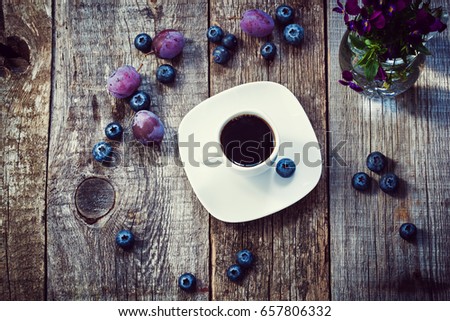 A cup of morning coffee decorated violet berries on old wooden background. Top view, concept of Pantone color of the year 2018 - ultra violet