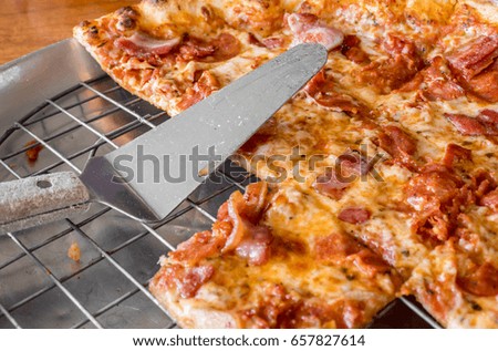 The close up picture of piece of Italian or American pizza on the tray with scoop , homemade or in restaurant. 