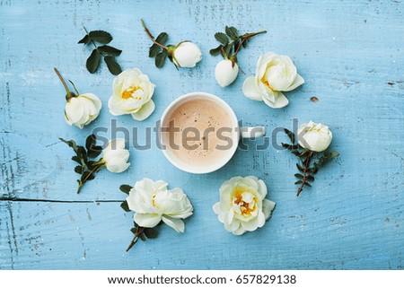Morning cup of coffee and beautiful roses flowers on blue vintage background top view. Cozy Breakfast. Flat lay style.