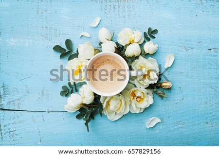 Morning cup of coffee and beautiful roses flowers on turquoise rustic table top view. Cozy Breakfast. Flat lay style.