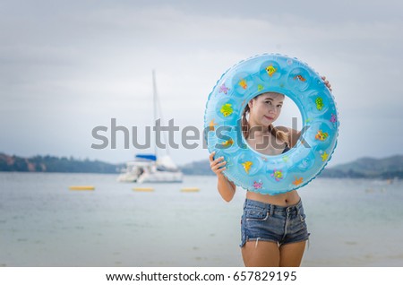 beautiful girl in bikini having fun on a tropical beach with rubber ring