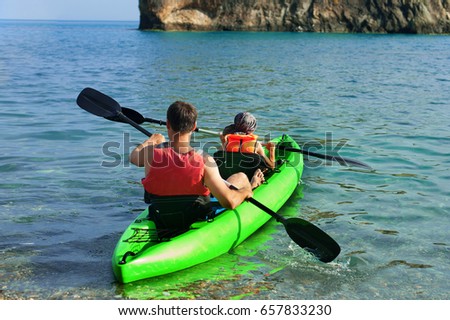 Two people - an adult and a child father and son in life jackets sail on inflatable boats during hike at summer