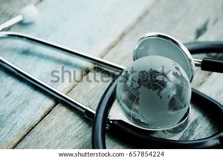close up glass global and stethoscope on wood table, business and healthcare concept, process vintage tone. Element of this image are furnished by NASA
