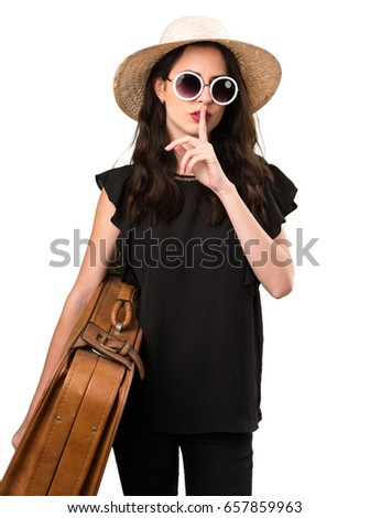 Beautiful young girl with  a suitcase making silence gesture