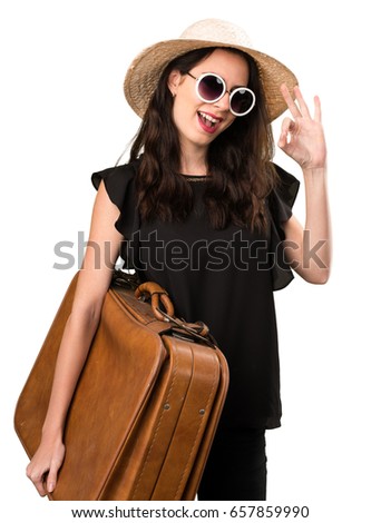 Beautiful young girl with  a suitcase making OK sign