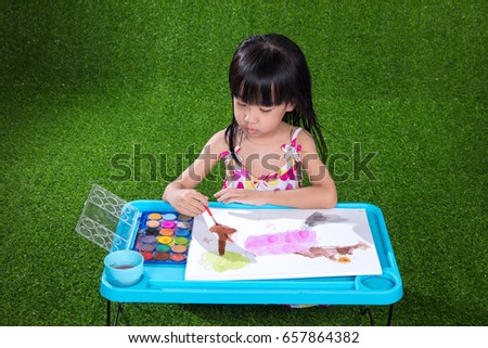 Asian Chinese little girl sitting on the grass drawing and painting