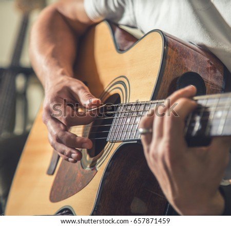 the guy playing the acoustic guitar, closeup, music concept