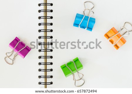 colorful binder clips spread on blank notebook 