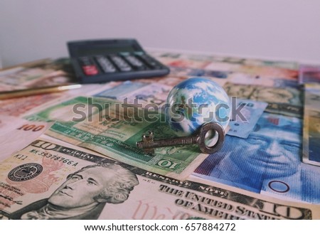World globe with key, calculator and pen on various money currency, global economy 