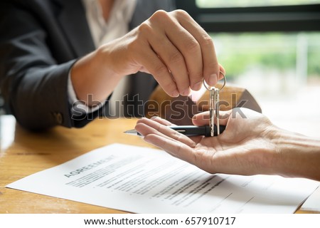 real estate agent holding house key to his client after signing contract agreement in office,concept for real estate, moving home or renting property  Royalty-Free Stock Photo #657910717