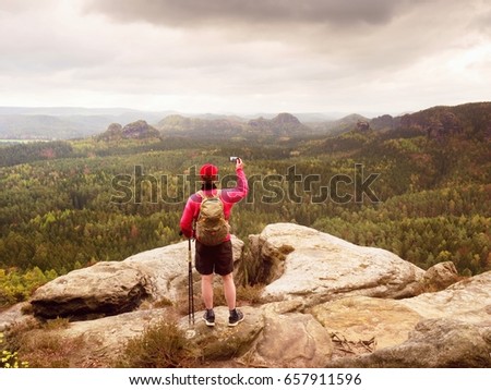 Mobile phone photographer. Tourist on the rocky edge take phone pictures. Hiking in mountains enrich life