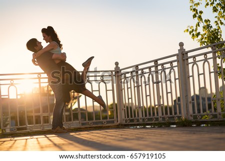 Beautiful young couple sitting on the river bank at sunset
