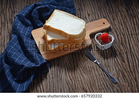 Sliced white breads on cupboard with strawberry jam in love cup with fresh strawberry on wooden table. Selective focus for designed works. Concept about love and relationship. Rustic Style