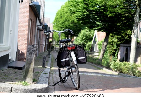 A bicycle with black storage parking on the well-environment street. Street good for bike. Bicycle parking space. Bike lane. Bicycle friendly environment. Bike for health. Healthy lifestyle.