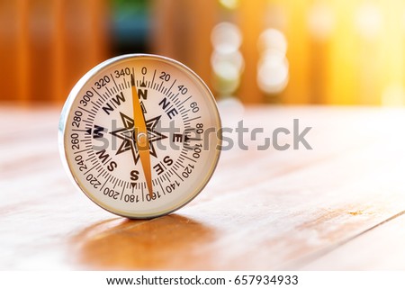 compass on wood table in sun light, find the right direction concept, start a new day with right direction concept
