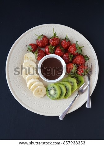 chocolate fondue with fresh fruits on a black background