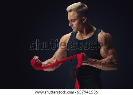 Strong man wrap hands on black background Man is wrapping hands with red boxing wraps isolated on black background Strong hands and fist, ready for training and active exercise