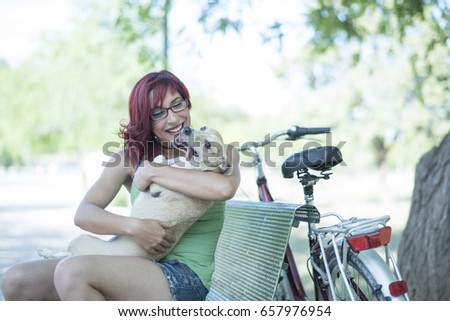 Woman with bicycle and dog in city park