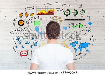 Back view of european guy looking at wooden wall with business sketch. Network concept