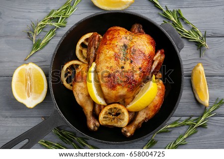 Homemade baked chicken with lemon on wooden background Royalty-Free Stock Photo #658004725