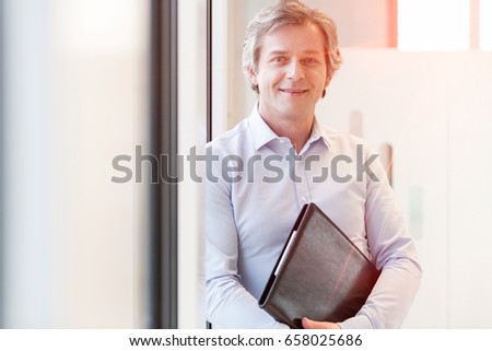Portrait of smiling mature businesswoman holding file in office