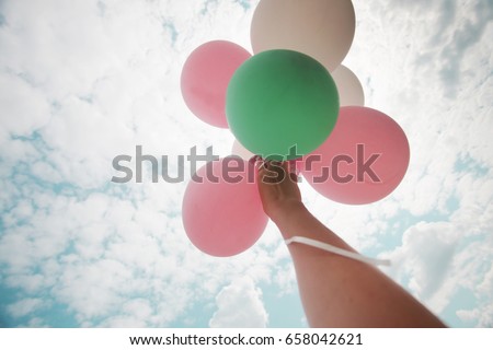 Woman hand holding balloons/ image with instagram filter effect - lifestyle concept in summer holiday