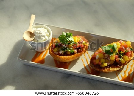 Mango and tomato salsa filled in baked potato skin, and served with cream cheese dipping sauce. All composition is placed under the yellow sunlight.
