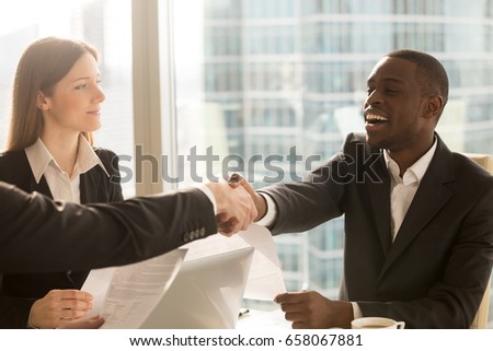 Making deal and shaking hands with smiling satisfied african-american client, multicultural partners handshaking, international businessmen signing agreement, effective negotiations under contract, HR