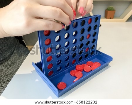 Woman plays bingo line up by picking round coin with red or black color make it 4 in a row on table.