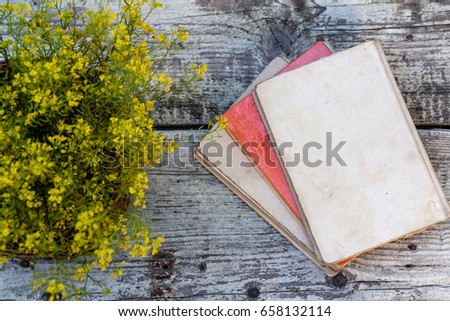 Old books and flower rose on a wooden background. Romantic floral frame background. Picture of a flowers lying on an antique book
