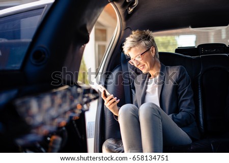 Businesswoman making phone call in limousine on exit