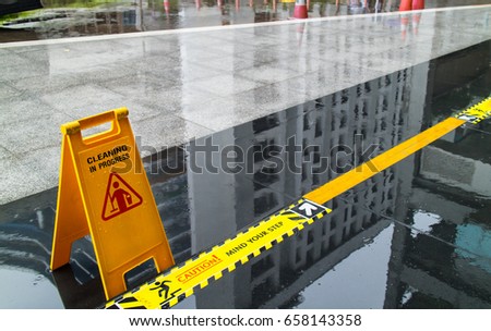 Sign showing warning of caution wet floor and mind the step in front of the building