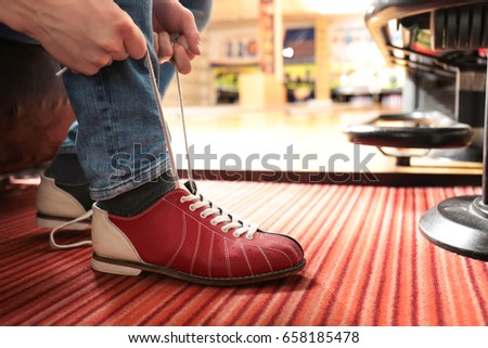 Young man lacing his shoes in bowling club