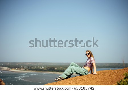 Beautiful happy woman in casual wear relaxing, lying on hill above the sea enjoying her touristic vocation holiday