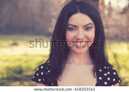Confident smiling happy woman, isolated on background of blurred trees. Positive human emotion feelings