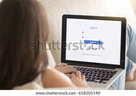 Woman lying on sofa with laptop enters email and password on web verification page. Female user passes security authorization system on her online banking account. Close up view over the shoulder