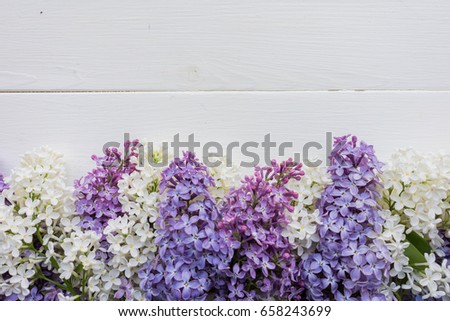 Background, frame with branches of lilac in different colors - white, lilac and purple on a white-painted wooden boards. Top view. Copy space. The theme of spring, summer, good morning. 