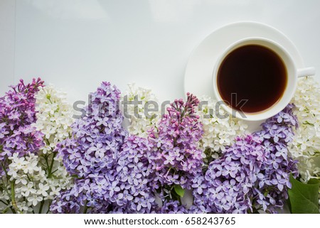 Background with branches of lilac in different colors - white, lilac and purple on a white and a Cup of black coffee Top view Copy space The theme of spring, summer, good morning
