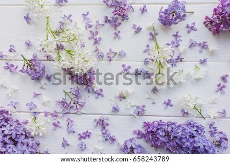 Twigs and small buds of lilac on white-painted wooden boards. Shabby chic. The theme of spring, summer. Top view. Bright and light background for postcards, banners, invitations, typographic item. 