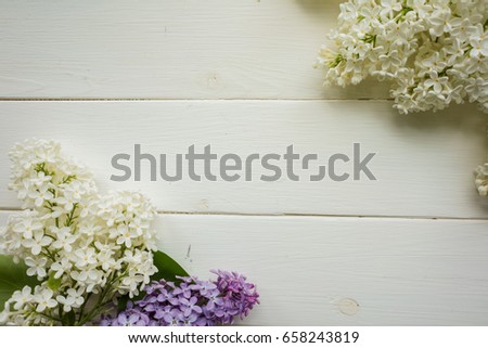 Background, frame with branches of lilac in different colors - white, lilac and purple on a white-painted wooden boards. Copy space. Top view. The theme of spring, summer, good morning. 