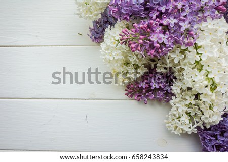 Background, frame with branches of lilac in different colors - white, lilac and purple on a white-painted wooden boards. Top view. Copy space. The theme of spring, summer, good morning.  