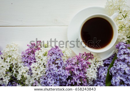Background with branches of lilac in different colors - white, lilac and purple on a white-painted wooden boards and a Cup of black coffee Top view Copy space The theme of spring, summer, good morning