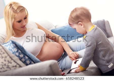 Picture of young Happy Pregnant woman playing with son