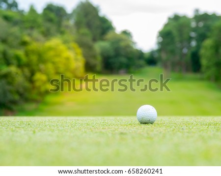 Golf concept. Golf ball on a green golf of course in a beautiful field. The beautiful of the golf course is visible layout and fairway in sunlight . Player can see beautiful forest sky and cloud 