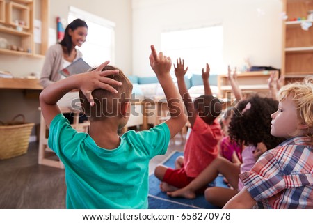 Pupils At Montessori School Raising Hands To Answer Question Royalty-Free Stock Photo #658270978