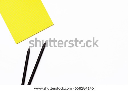 Two black pencil and a yellow Notepad on a white background. Minimal business concept of working place in the office. Flat lay. Top view.