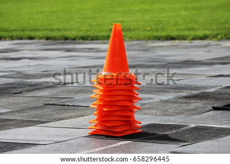 Plastic orange signal cones stand at the stadium in preparation for the competition for lifting weights.