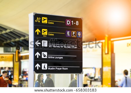 Yellow illuminated sign at airport with gate arrow for departing flights