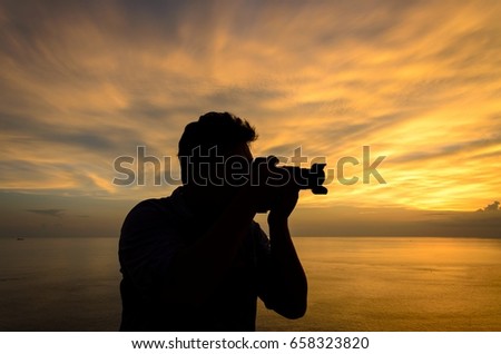 Silhouette of photographer on the beach  taking pictures of the beautiful moments during the sunset  with dramatic sky